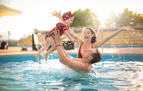 Happy family playing in an inground swimming pool.